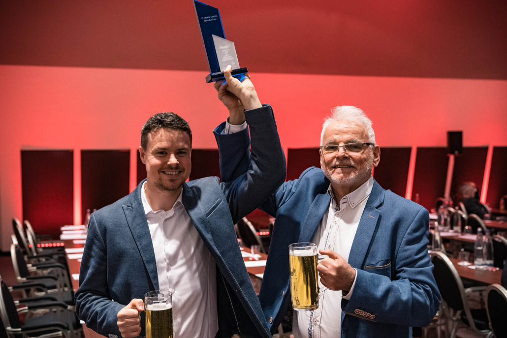 Zwei Männer mit Bier und Auszeichnung.