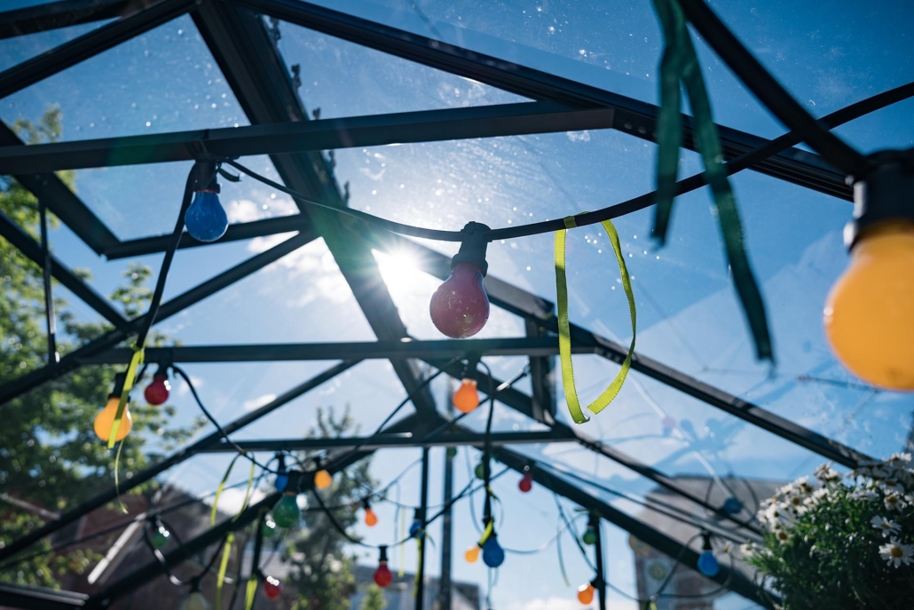 Lichterkette im Gewächshaus bei Sonnenlicht