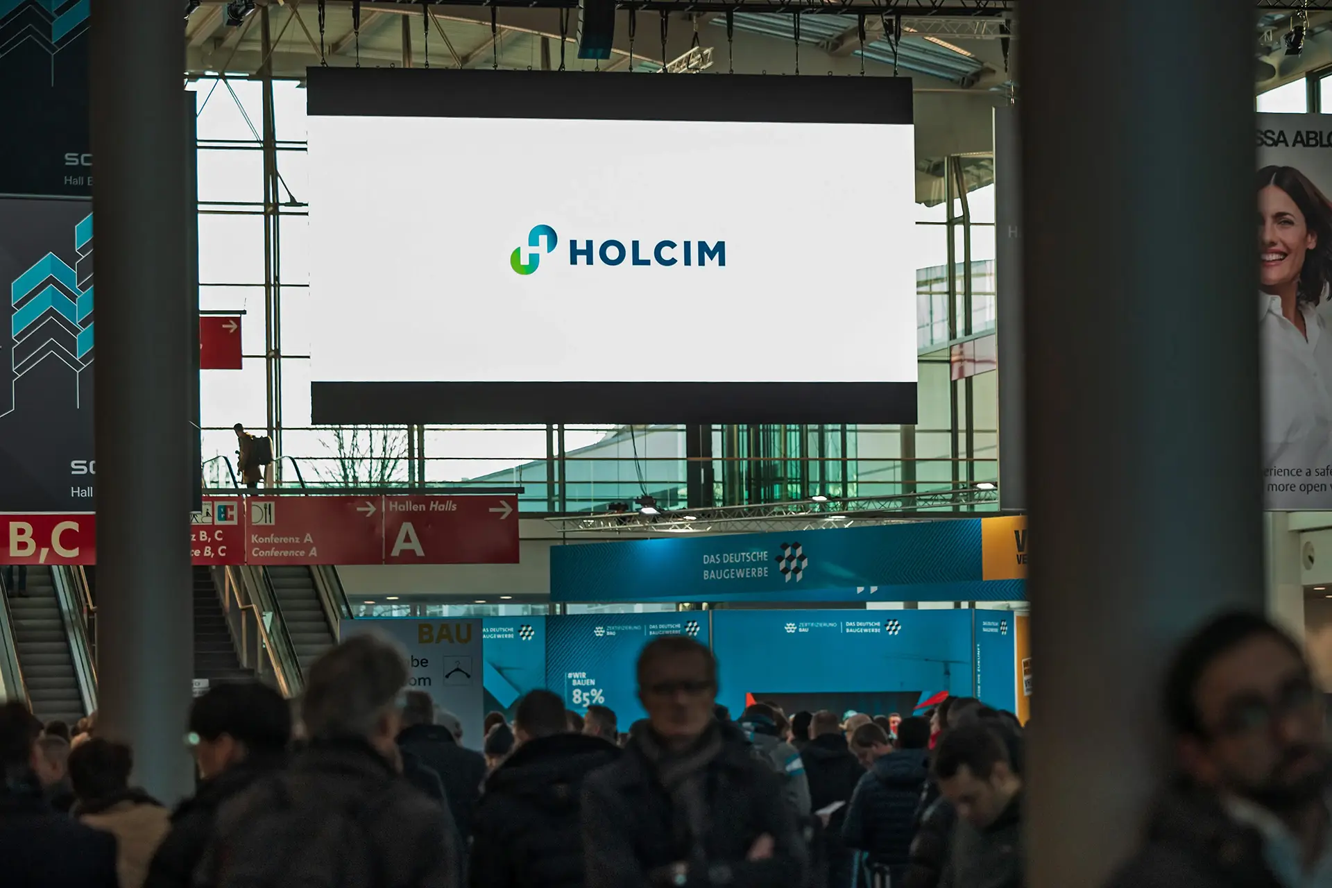 Menschenmenge unter Holcim-Werbung